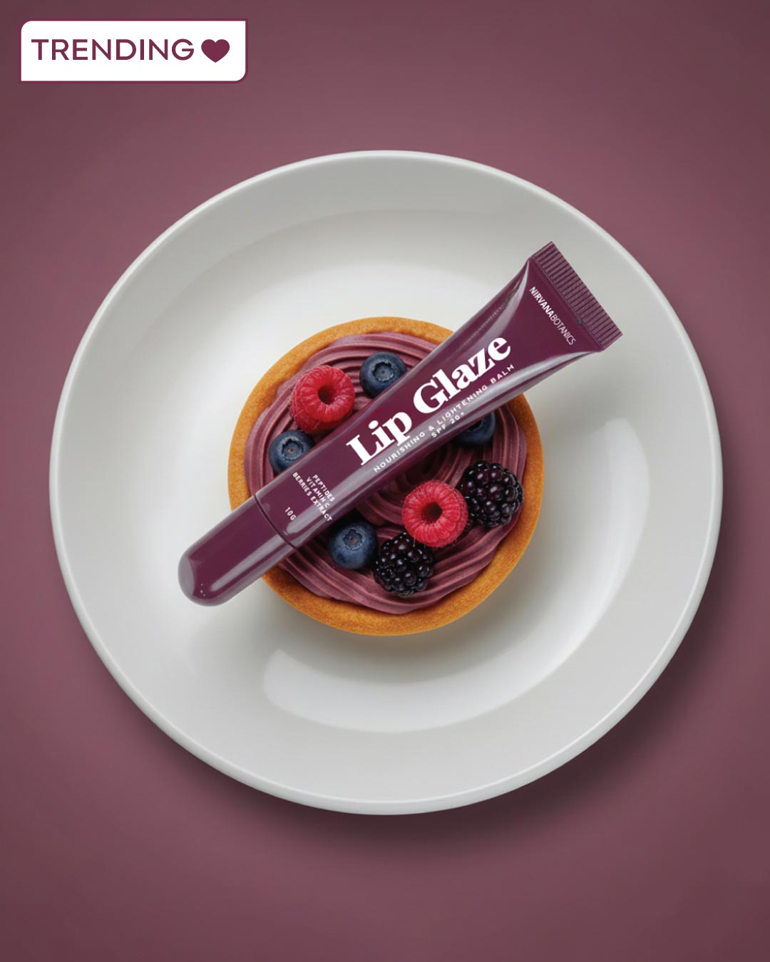 Lip Glaze product on a dessert with berries on a white plate against a purple background