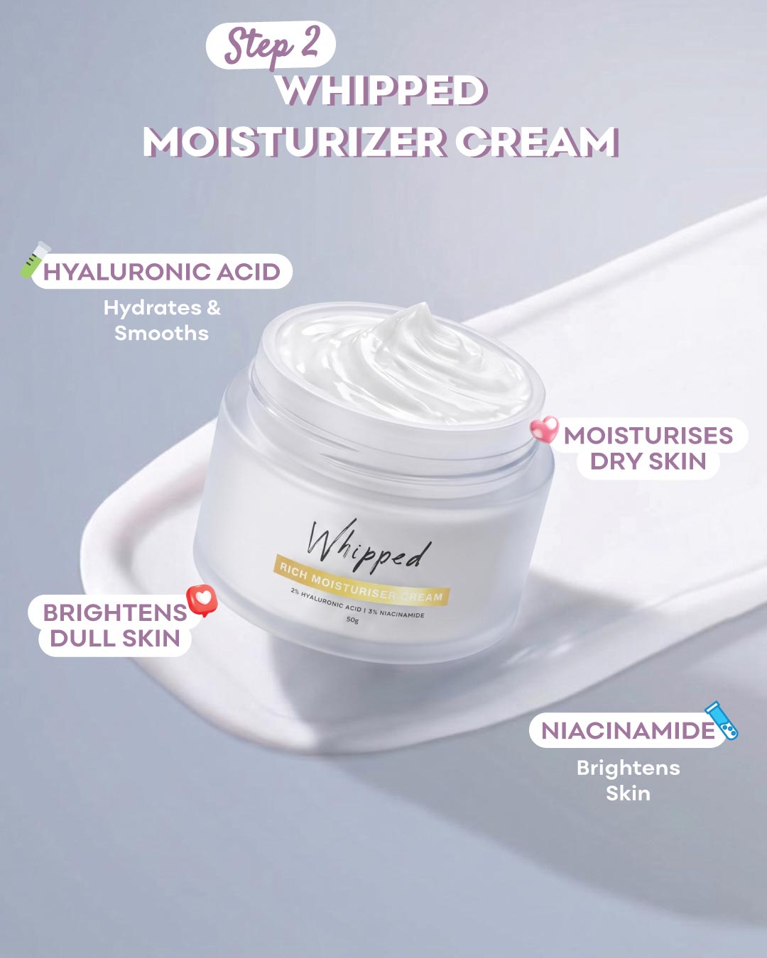 A jar of Whipped Step 2 Whipped Moisturizer Cream shown on a white spatula against a pale blue-gray background, with text callouts highlighting key ingredients and benefits.