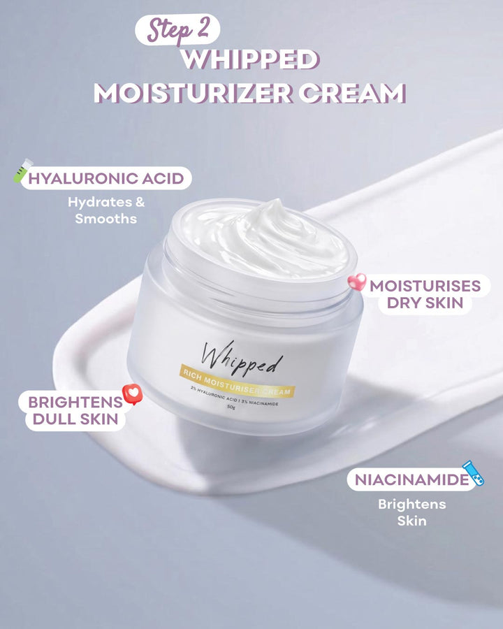A jar of Whipped Step 2 Whipped Moisturizer Cream shown on a white spatula against a pale blue-gray background, with text callouts highlighting key ingredients and benefits.
