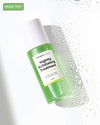 Green and white bottle of 'Nightly Exfoliating Treatment' with droplets on a light background