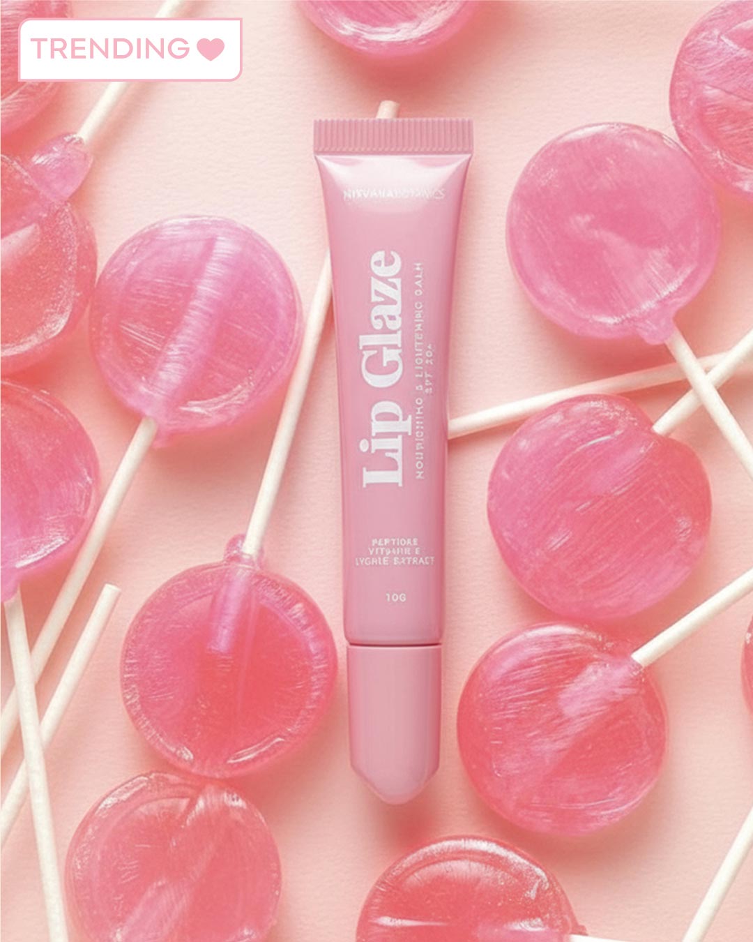 Pink lip gloss tube surrounded by pink lollipops on a pink background