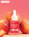 PeachCinamide TXA Serum bottle with peaches on a pink background