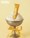 Lip glaze tube with whipped cream and a bow on a yellow background