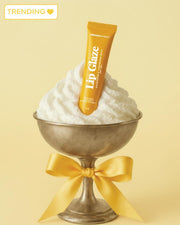 Lip glaze tube with whipped cream and a bow on a yellow background