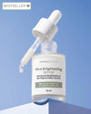 Nirvana Botanics Rice Brightening Serum in a clear glass dropper bottle with a white dropper, shown against a blue gradient background with a 'BESTSELLER' badge in the top left corner.